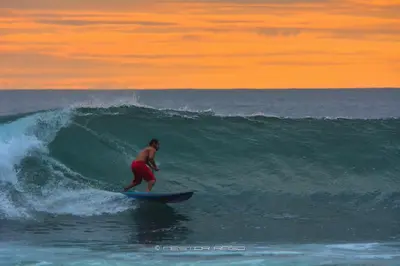 a man riding a wave on a surfboard in the ocean at Vida Hermosa in Playa Hermosa