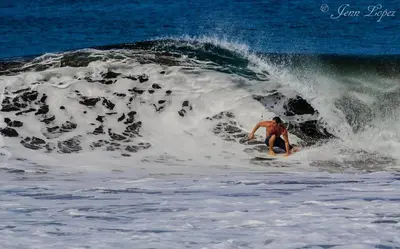 a man riding a wave on a surfboard in the ocean at Vida Hermosa in Playa Hermosa