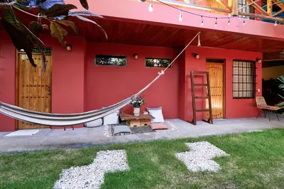 a red house with a hammock in the yard at Casa Calocita in Santa Teresa Beach