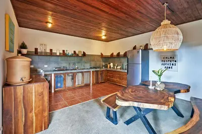 a kitchen with a wooden table and a refrigerator at Casa Calocita in Santa Teresa Beach