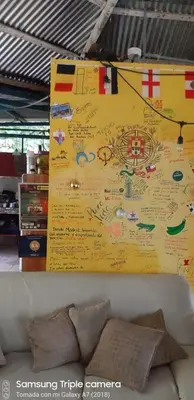 a yellow wall with writing on it next to a couch at Hostal y cabinas anita-and rafting tour! in Siquirres