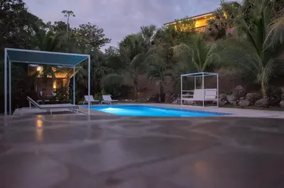 a swimming pool with two chairs and a gazebo at Rancho Capulin B&B in Tarcoles