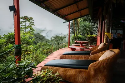 a patio with wicker chairs and a table on a building at Santa Juana Lodge & Nature Reserve in Quepos
