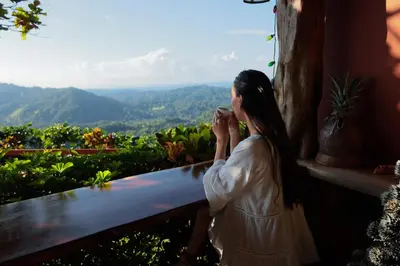 a woman sitting on a bench looking out at the mountains at Santa Juana Lodge & Nature Reserve in Quepos