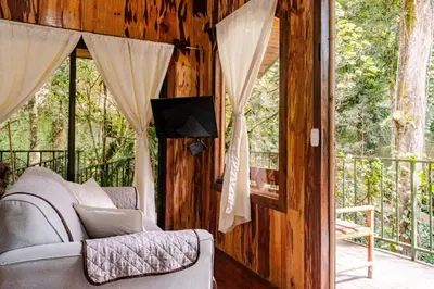 a living room with a couch and a screened in porch at Monteverde Romantic Cabañas 5minutes mtv park in Monteverde Costa Rica