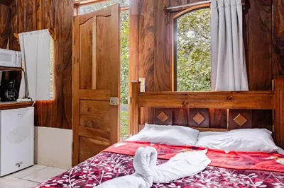 a bedroom with a bed and a window and a door at Monteverde Romantic Cabañas 5minutes mtv park in Monteverde Costa Rica