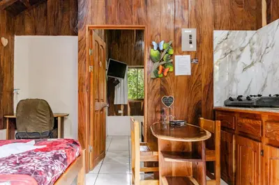 a room with a table and a kitchen with wooden walls at Monteverde Romantic Cabañas 5minutes mtv park in Monteverde Costa Rica