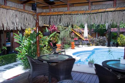 a patio with tables and chairs next to a swimming pool at Samara Palm Lodge in Sámara