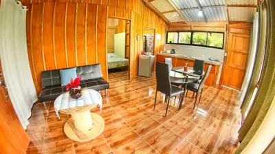 a living room with a table and a kitchen at Cabañas del Lago in Fortuna