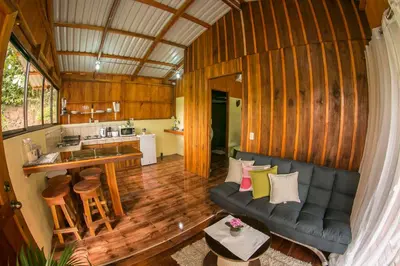 a living room with a couch and a kitchen at Cabañas del Lago in Fortuna