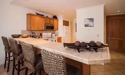 a kitchen with a counter with chairs around it at Ocean View Condo in Los Sueños in Herradura