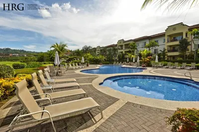 a group of lounge chairs and a swimming pool at Ocean View Condo in Los Sueños in Herradura
