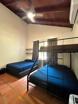 two bunk beds in a room with blue sheets at Tamarindo Backpackers in Tamarindo
