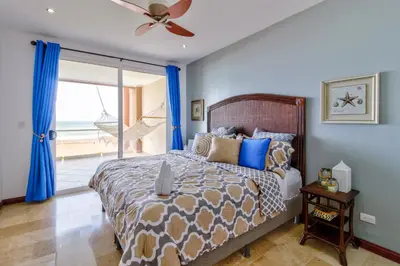a bedroom with a bed with blue walls and a window at Breakwater Point 602 in Jacó