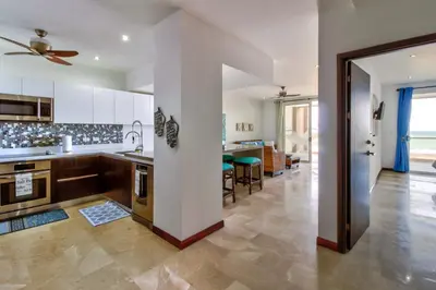a kitchen with white cabinets and a living room at Breakwater Point 602 in Jacó
