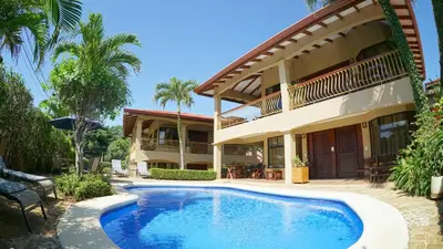 a villa with a swimming pool in front of a house at Villas Welcome to Heaven in Carrillo