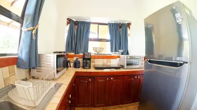 a kitchen with wooden cabinets and a stainless steel refrigerator at Villas Welcome to Heaven in Carrillo
