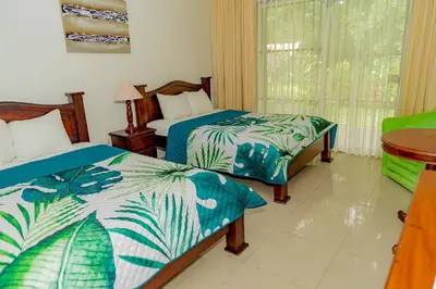 a hotel room with two beds and a window at Hotel Los Rios in Guácimo