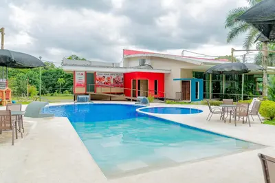 a swimming pool in front of a house at Hotel Los Rios in Guácimo