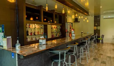 a bar with a row of stools in a restaurant at Hotel Los Rios in Guácimo