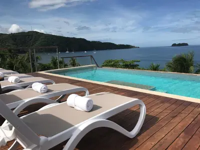 a swimming pool with lounge chairs on a deck at Hotel La Gaviota Tropical in Playa Hermosa