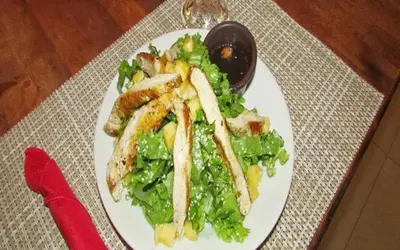 a plate of food with chicken and salad on a table at Hotel La Gaviota Tropical in Playa Hermosa