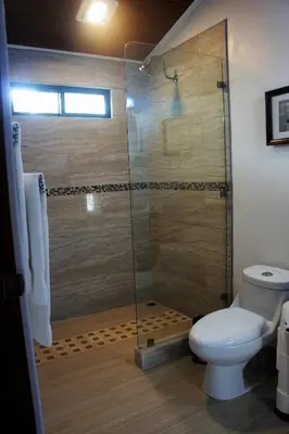 a bathroom with a glass shower with a toilet at Casa Donna Rosa B&B in Nuevo Arenal