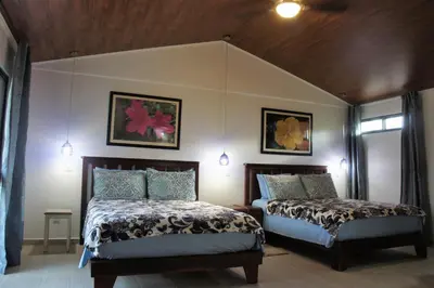 a bedroom with two beds and two windows at Casa Donna Rosa B&B in Nuevo Arenal
