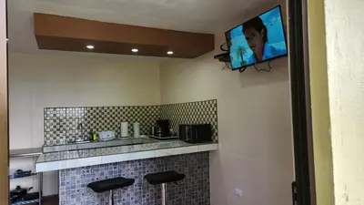 a kitchen with a tv on a wall with stools at La Guayaba Monteverde in Monteverde Costa Rica