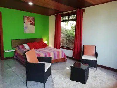a bedroom with a bed and two chairs and a window at La Guayaba Monteverde in Monteverde Costa Rica
