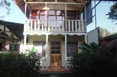 a white house with a balcony and a porch at Quinta los volcanes in Turrialba