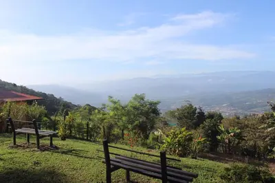 two benches sitting on top of a hill with a view at Quinta los volcanes in Turrialba