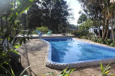 a large swimming pool in a yard with a patio at Quinta los volcanes in Turrialba