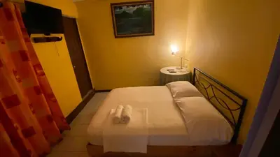 a small bedroom with a bed and a television at Hostel Pura Vida en Liberia in Liberia