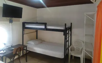 a room with two bunk beds and a desk and a chair at Hostel Pura Vida en Liberia in Liberia