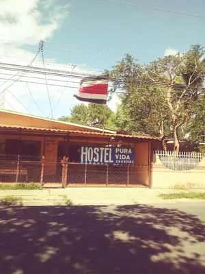 a hostel with a sign on the side of a building at Hostel Pura Vida en Liberia in Liberia