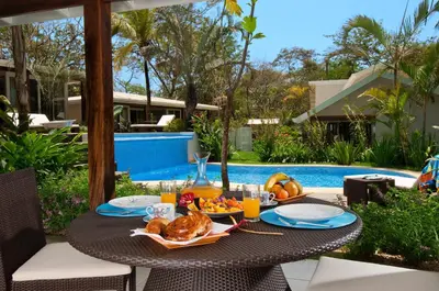a table with food and drinks on it next to a pool at The Breeze Hotel & Villas in Tamarindo