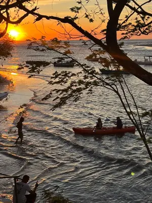 a group of people in a canoe on the water at sunset at The Breeze Hotel & Villas in Tamarindo