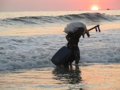 a person walking into the water on the beach at Light of Dawn in Quepos