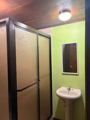 a green bathroom with a sink and a mirror at Hospedaje Angeluz in Quesada