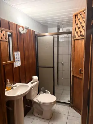 a bathroom with a toilet and a sink and a shower at Hospedaje Angeluz in Quesada