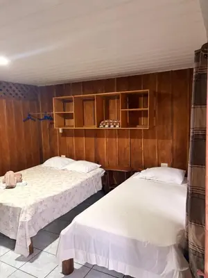 two beds in a room with wooden walls at Hospedaje Angeluz in Quesada
