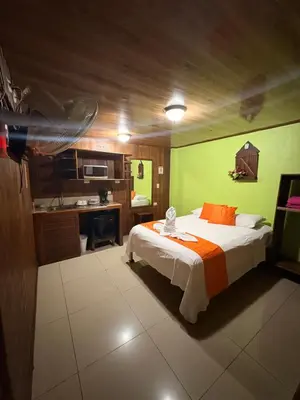 a bedroom with a large bed and a kitchen at Hospedaje Angeluz in Quesada