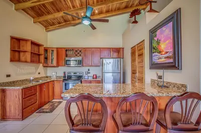 a kitchen with wooden cabinets and a ceiling fan at Hidden Palms in Nosara