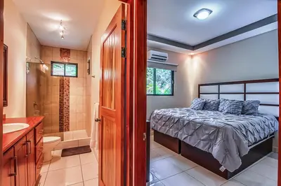 a bedroom with a bed and a bathroom with a shower at Hidden Palms in Nosara