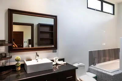 a bathroom with a sink and a mirror and a toilet at Hidden Palms in Nosara
