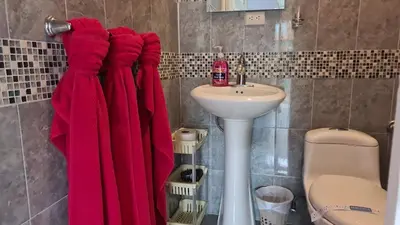 a bathroom with a red robe hanging next to a sink at El Encanto Condominiums in Jacó