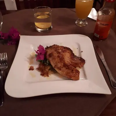 a white plate with a piece of chicken on a table at Hotel Hacienda El Rodeo in Rodeo
