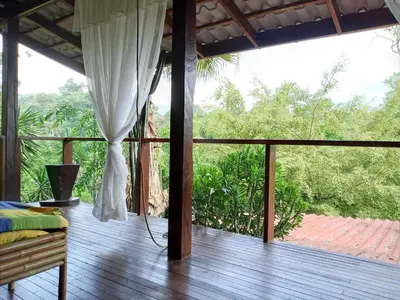 a porch with a bed and a balcony with trees at Princesa de la Luna Ecolodge in Fortuna