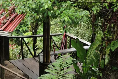 a wooden bridge with a red umbrella and a bench at Princesa de la Luna Ecolodge in Fortuna